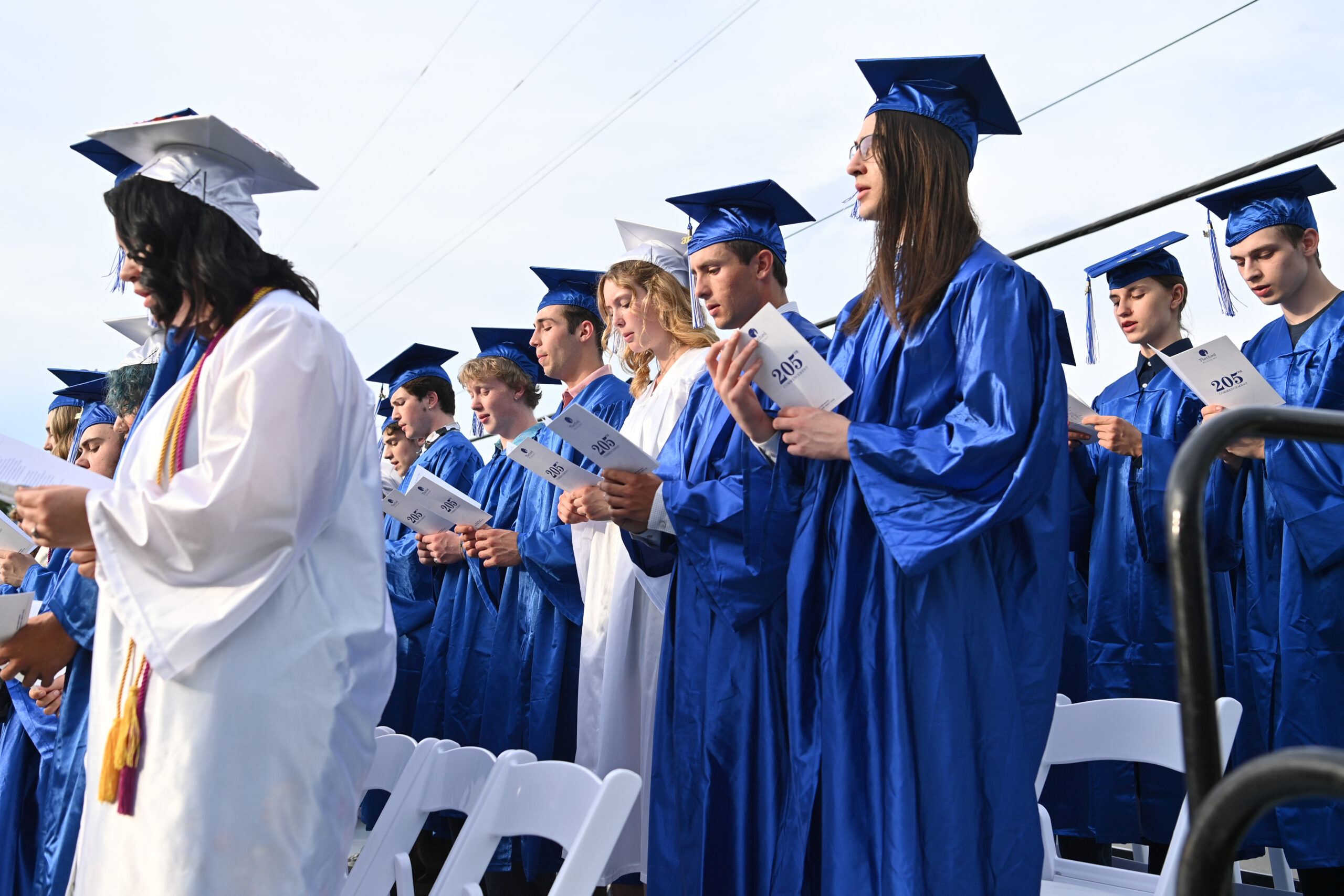 Graduates from the Class of 2024 sing the alma mater in caps and gowns.