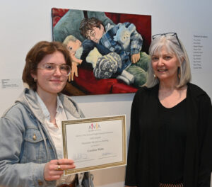 Student Caroline Watts and art teacher Karyn Neubauer pose with Caroline's painting and honorable mention certificate.